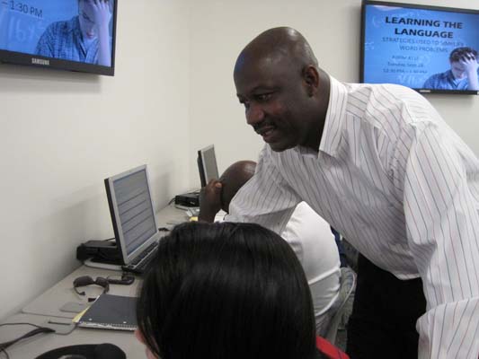 Math professor Peter Agbakpe helps a student at a computer