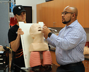 two EMS students work on a dummy patient