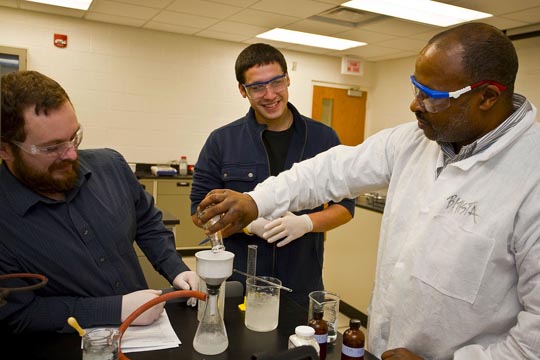 Professor Eric Hayes works with students in a chemistry lab