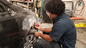 Student working on the outside of a car body