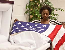 A student practices placing an American flag on a casket
