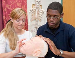 Two students work on a wax model during a restorative art class