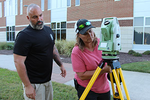 Two students work together with land surveying equipment