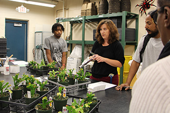 Horticulture instructor speaks to students while holding plants