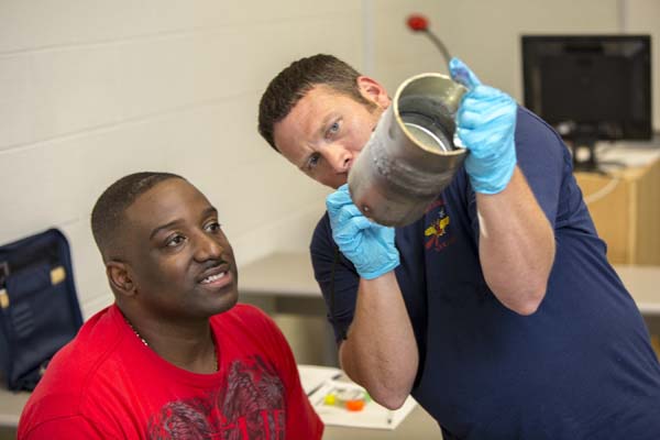 Chad Williamson showing classmate Willie Dixon a resultant defect found in a weld on a test piece used during a dye penetrant test demonstration