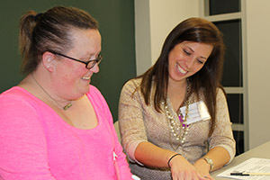 two smiling women looking at paperwork
