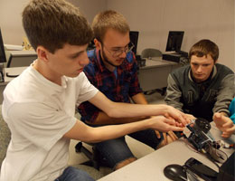 Three TCC engineering students work on building a robot.