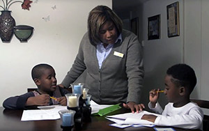 Mother helping two young boys with homework at a table