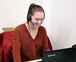 Woman wearing headset smiling in front of a computer